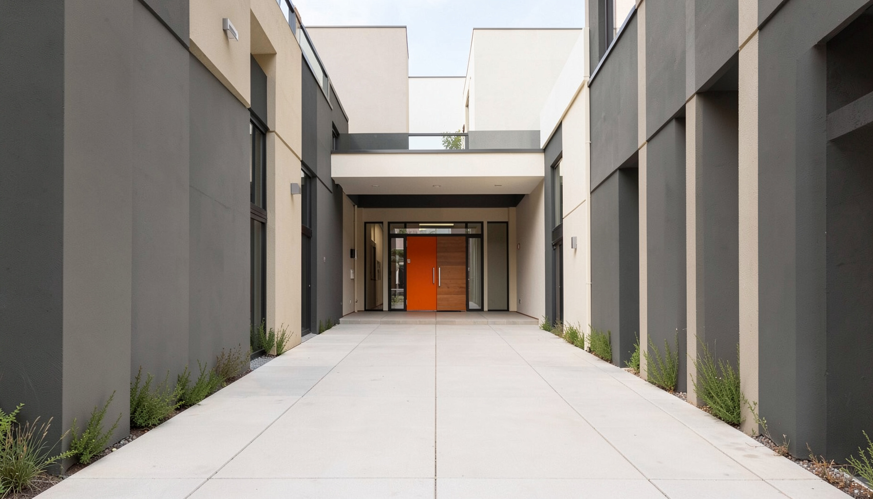 A clean symmetrical entrance walkway to a housing community building, muted charcoal and warm off-white tones, orderly and welcoming mood